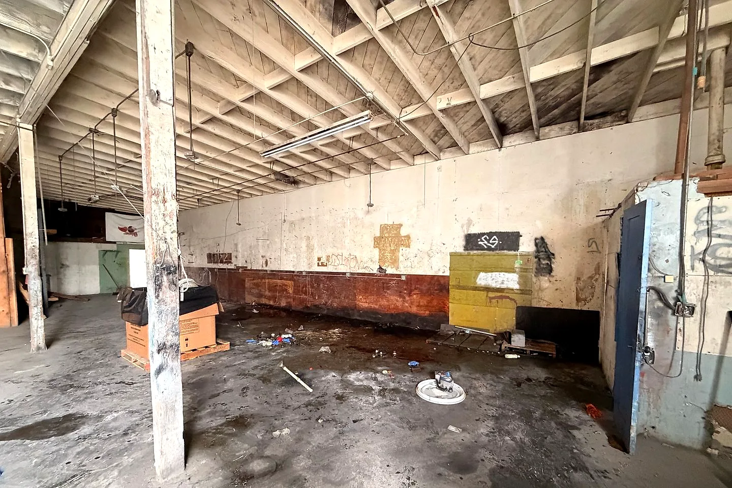 The same vacant industrial building with the drums and containers removed and the floor clear